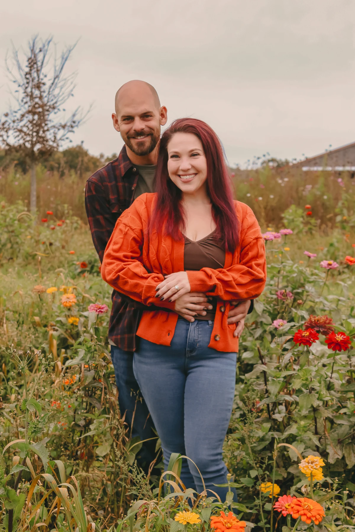 Engaged couple embracing among colorful autumn flowers