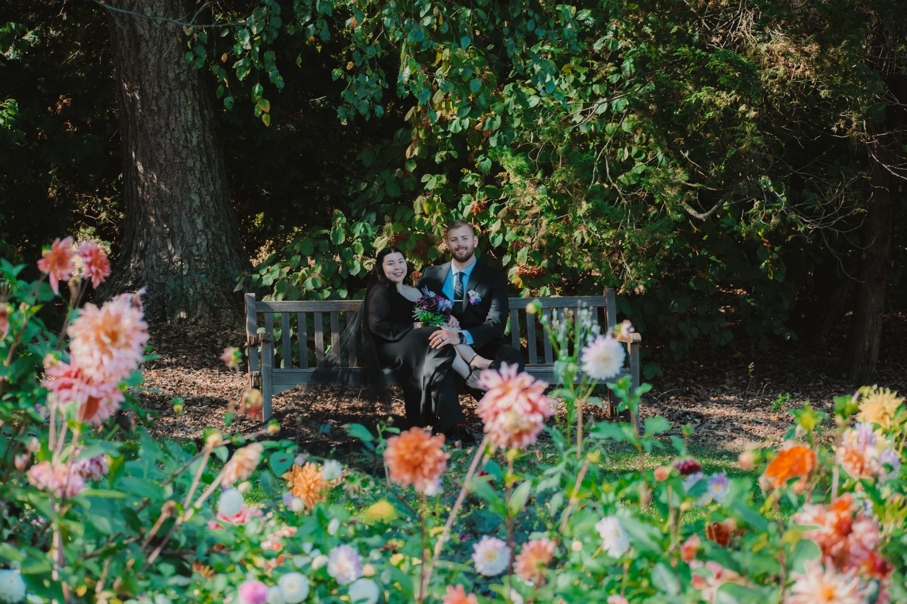 Emi and Mike together on a garden bench framed by colorful flowers