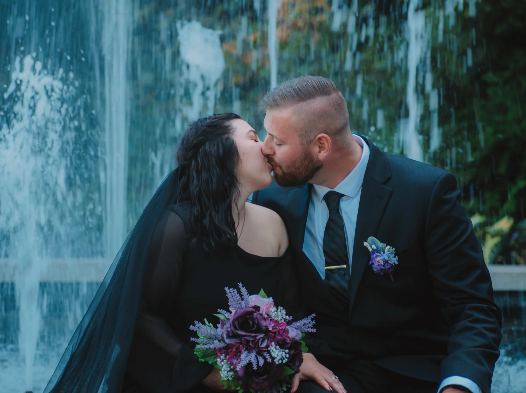 Emi and Mike sharing a kiss beside the garden fountain