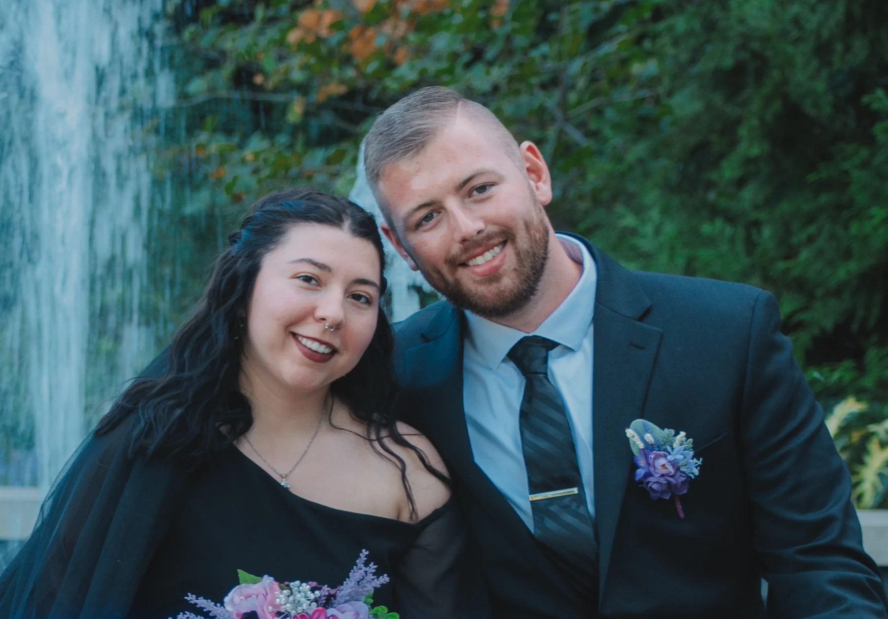 Emi and Mike leaning together and smiling beside the fountain