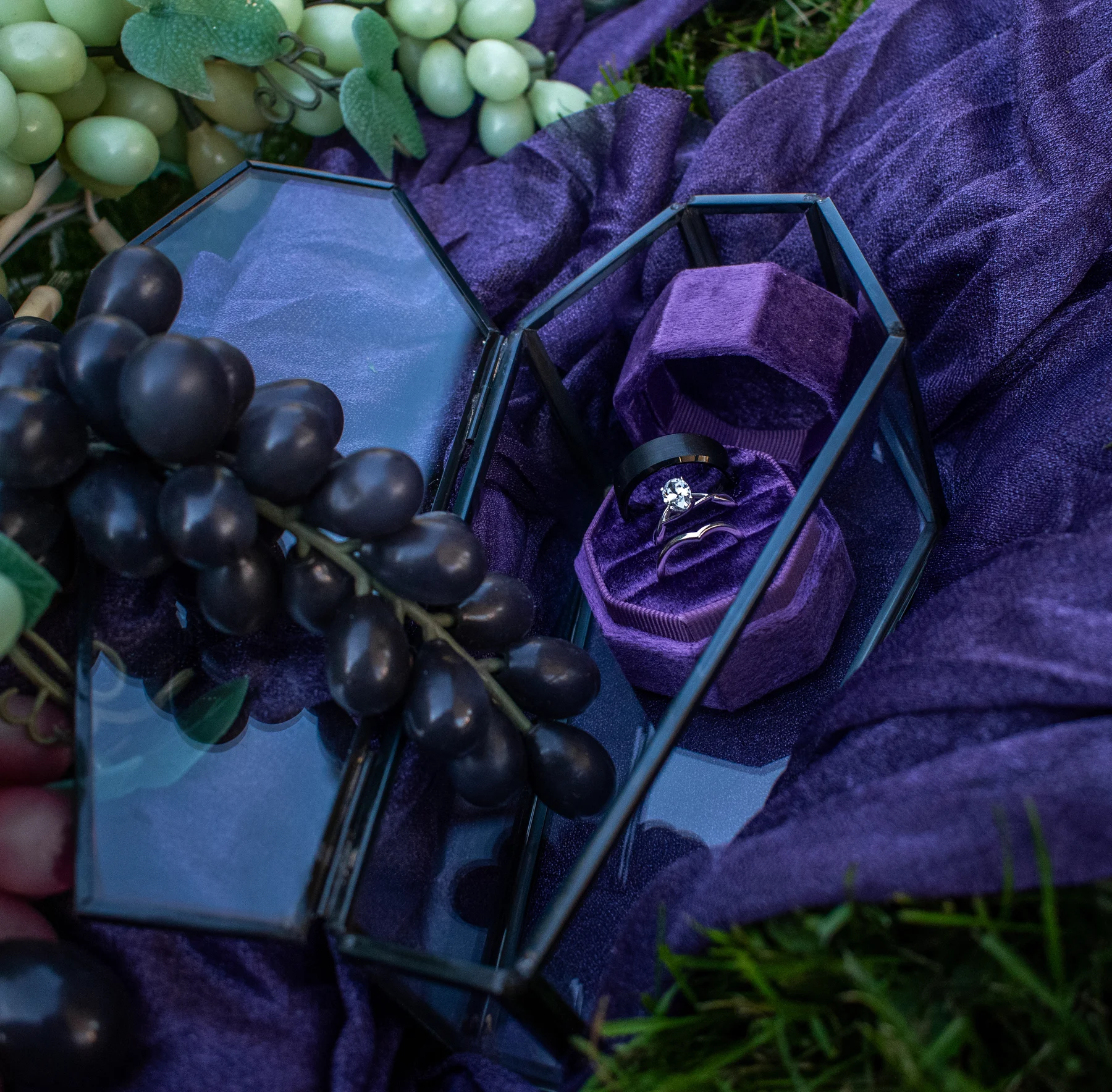 Wedding rings in purple velvet coffin-shaped boxes among dark florals