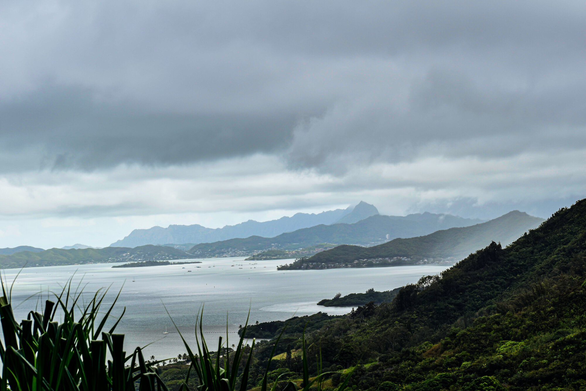 Sweeping view of a Hawaiian coastline with mountains under moody clouds