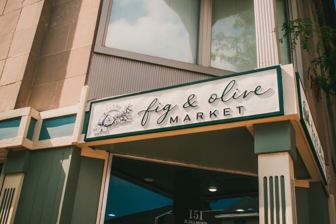 Hand-lettered Fig & Olive Market storefront sign above the shop entrance