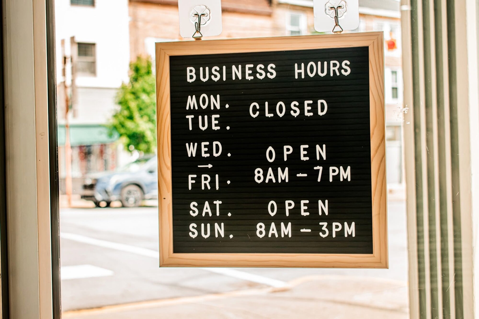 Letter-board business hours sign hanging in the market window