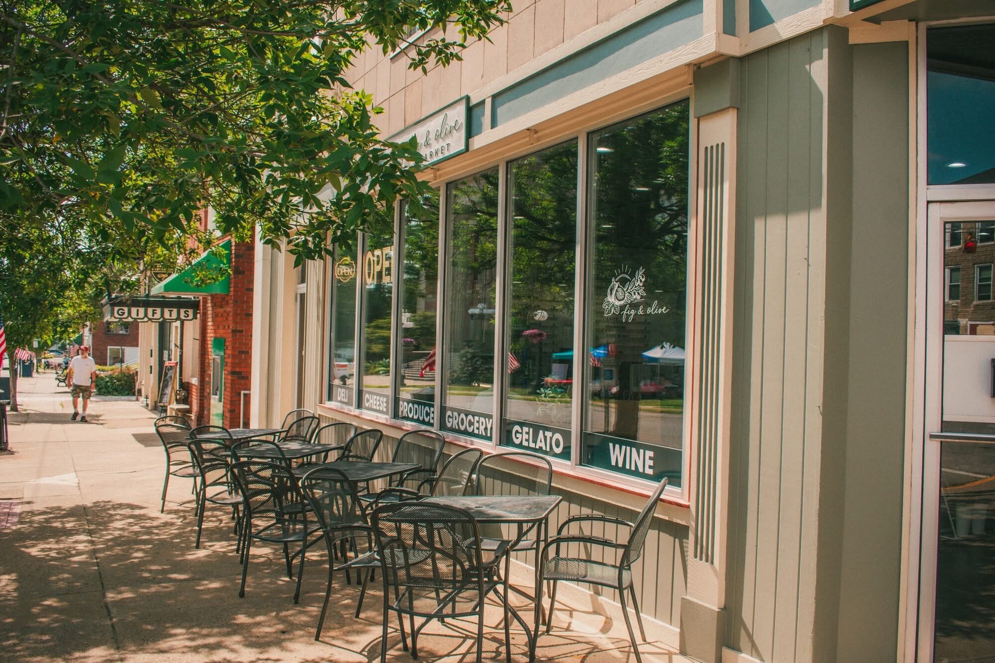 Sidewalk cafe seating outside a small-town specialty grocery storefront