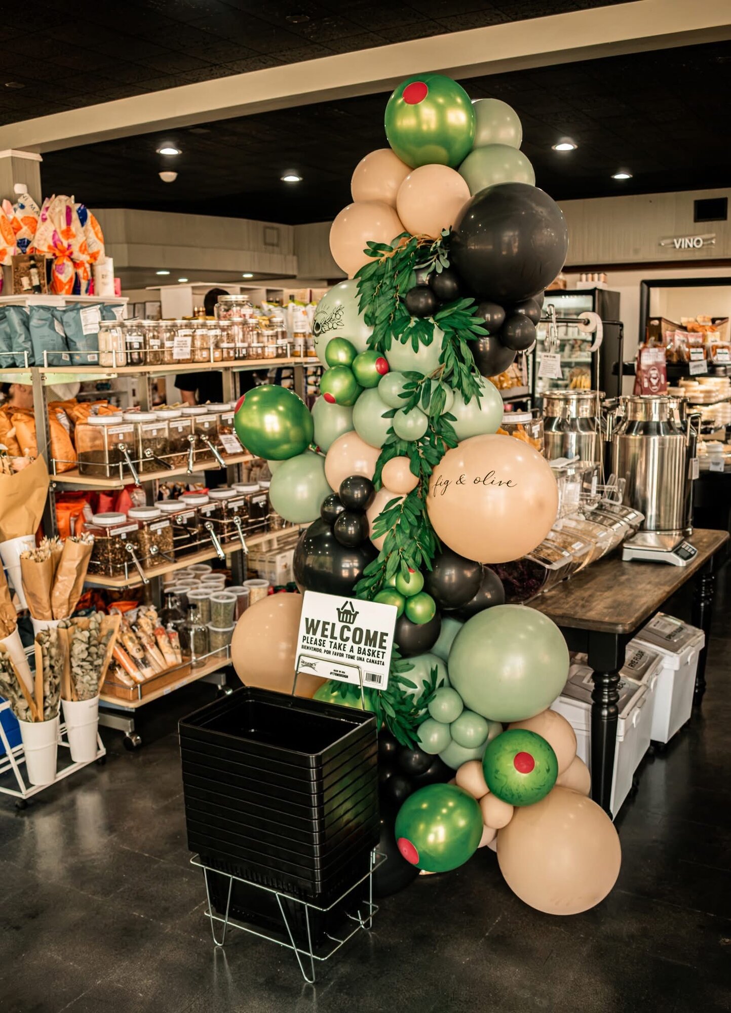 Olive-themed balloon garland welcoming shoppers inside the market