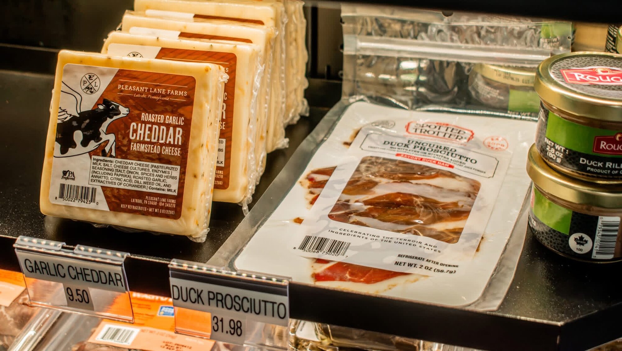 Specialty cheese and charcuterie display with garlic cheddar and duck prosciutto