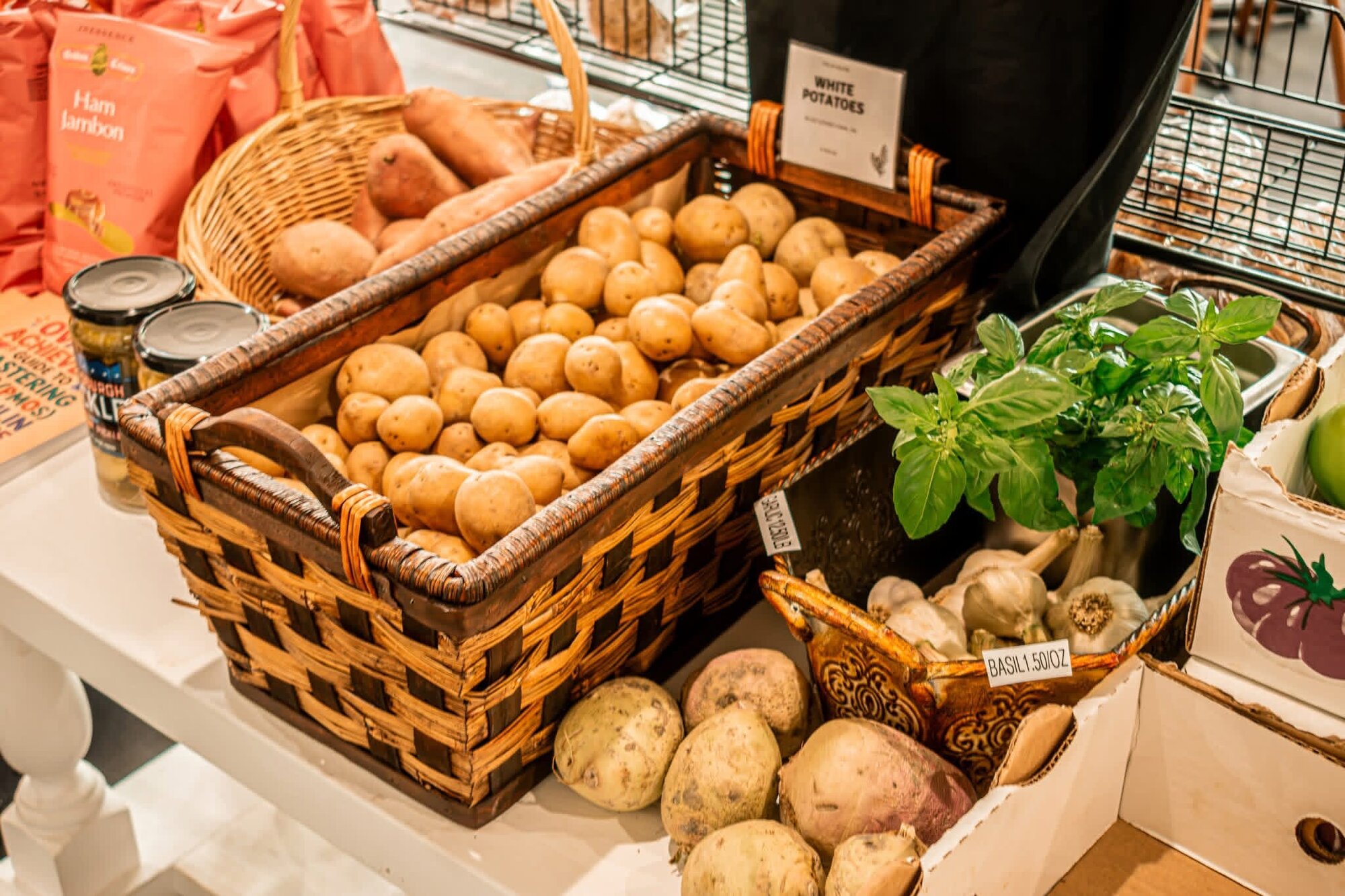 Woven basket of fresh potatoes and herbs on a market produce table