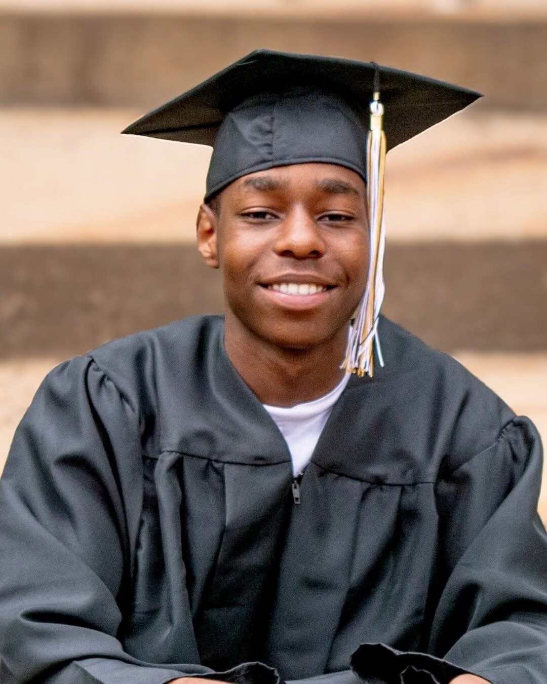 Senior graduation portrait of an adult in cap and gown with gold tassel