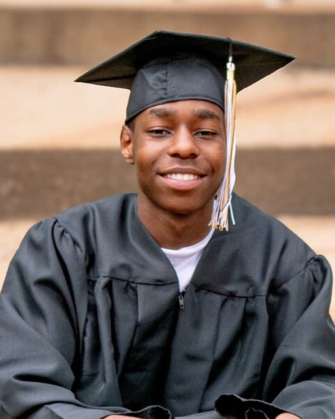 Senior graduation portrait of an adult in cap and gown with gold tassel