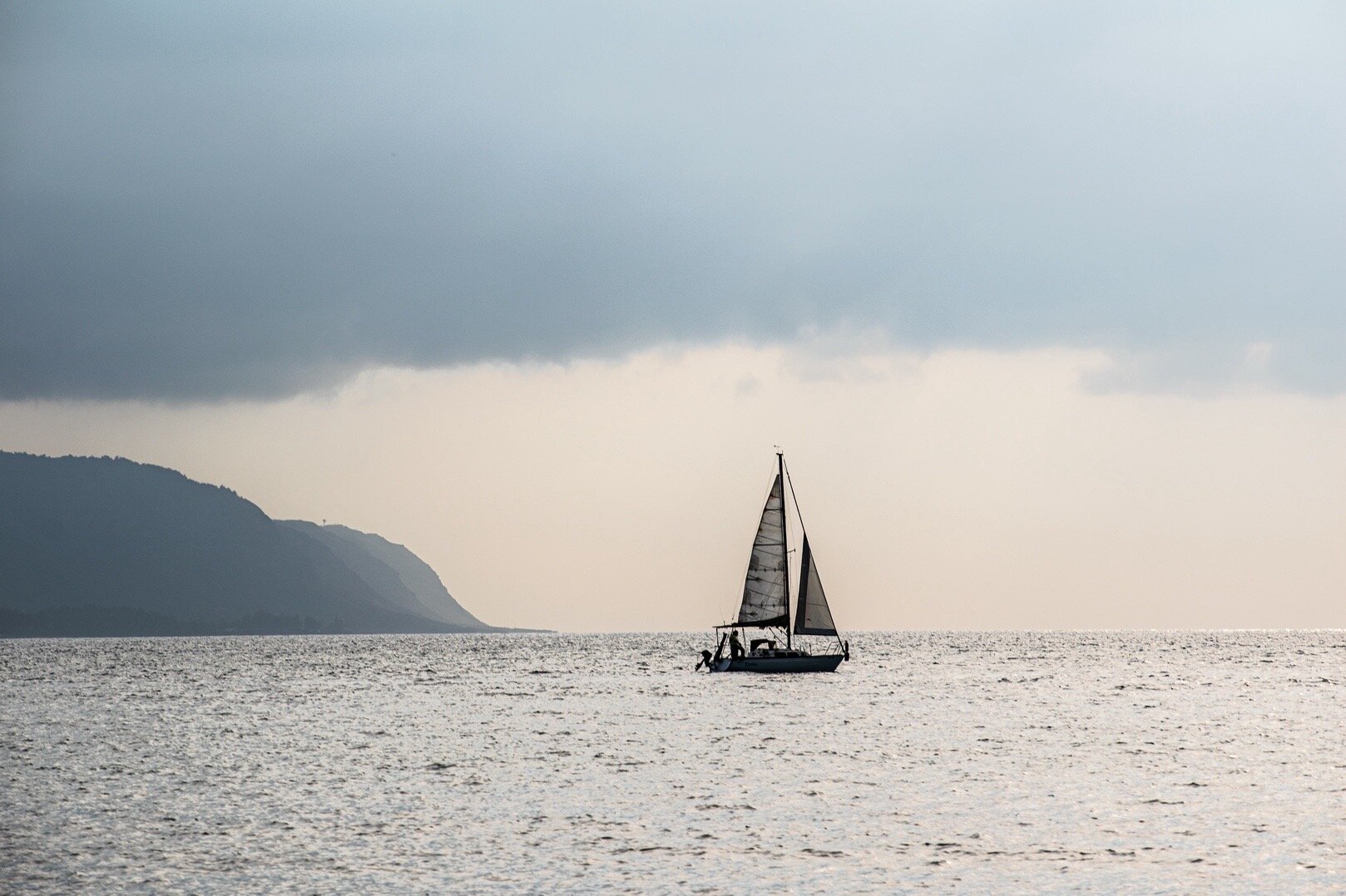 Sailboat off the Hawaiian coast in misty evening light