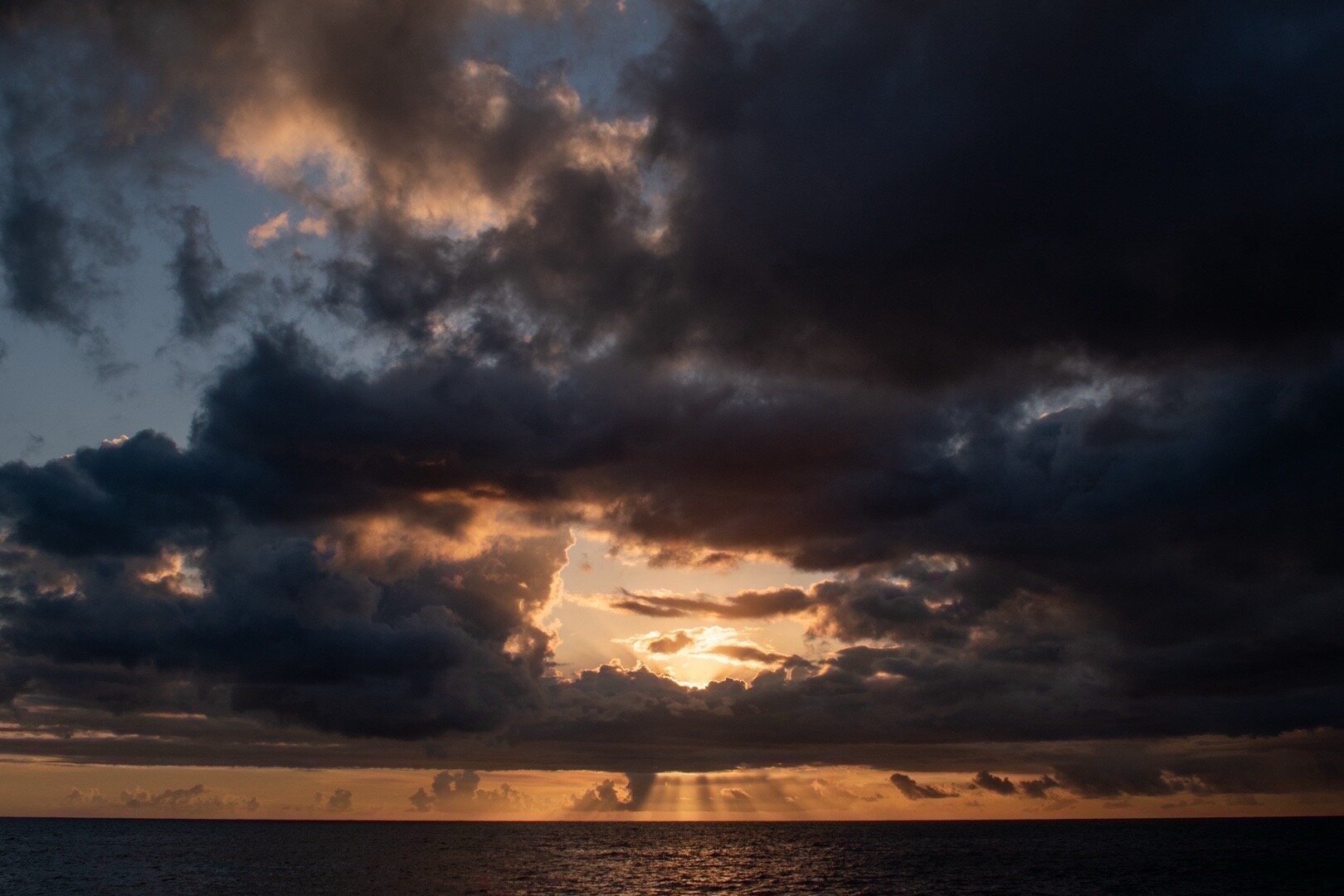 Sunbeams breaking through dramatic storm clouds over the sea