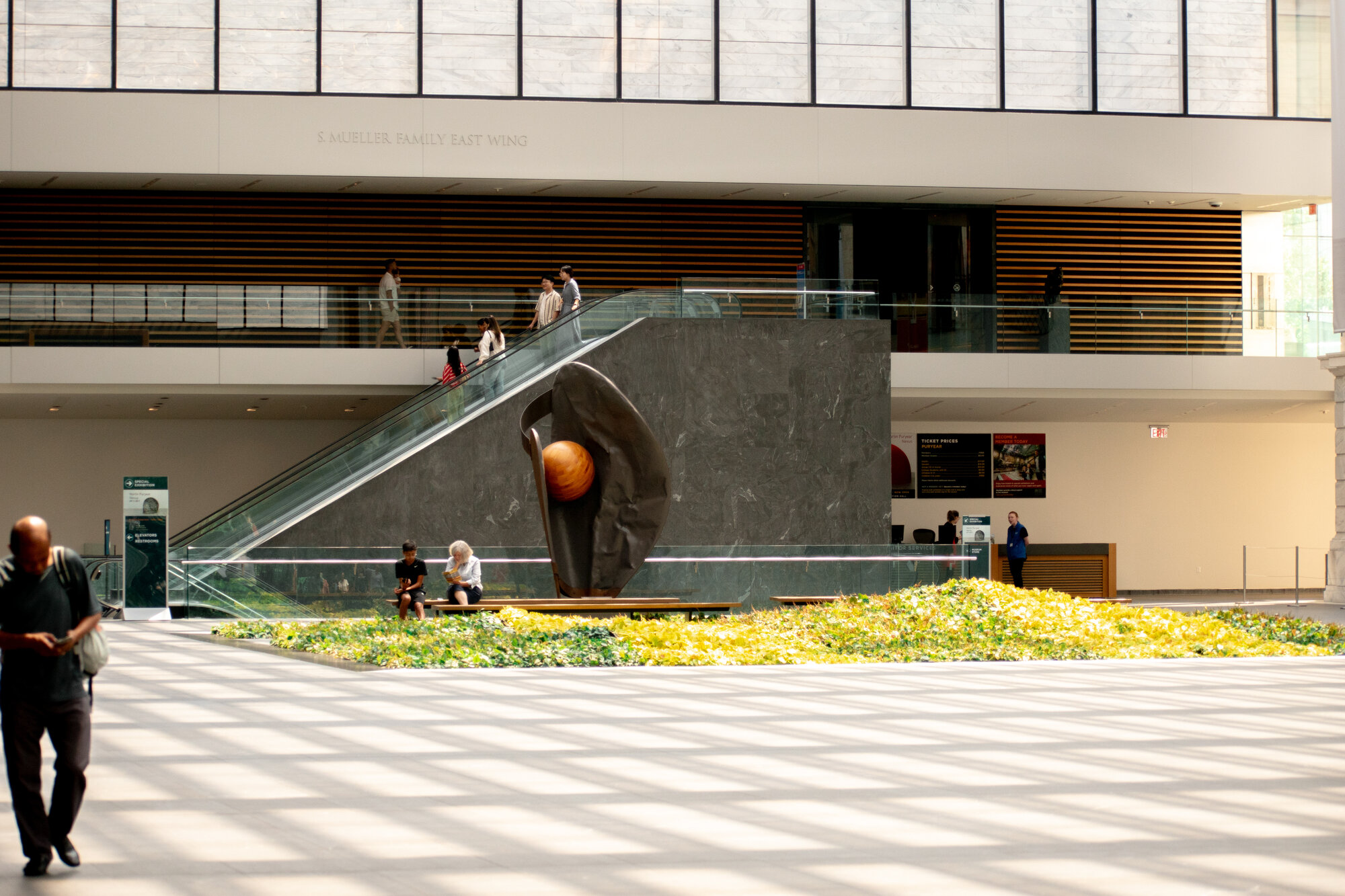Modern sculpture and escalator in a light-filled museum east wing atrium