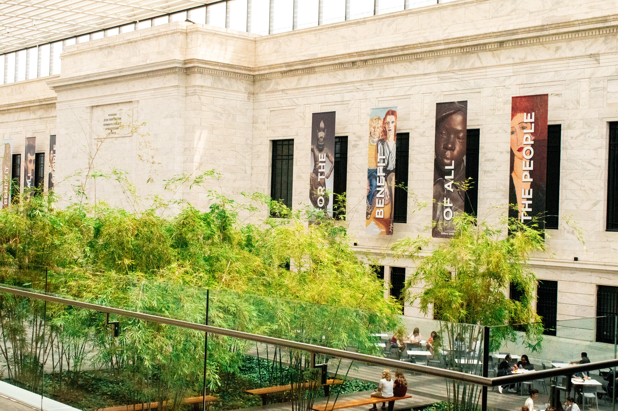 Marble museum facade with portrait banners rising above a bamboo courtyard