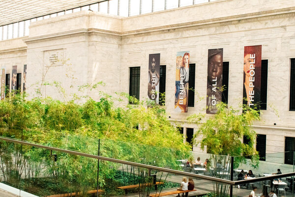 Marble museum facade with portrait banners rising above a bamboo courtyard
