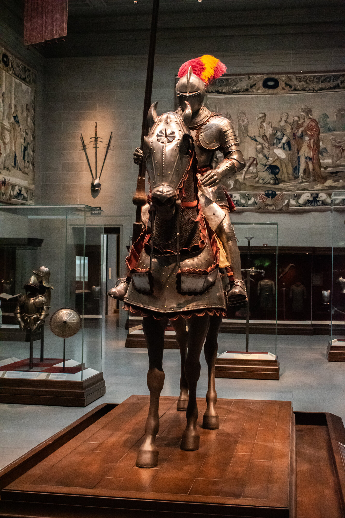 Knight in full plate armor on an armored horse, museum gallery with medieval tapestries