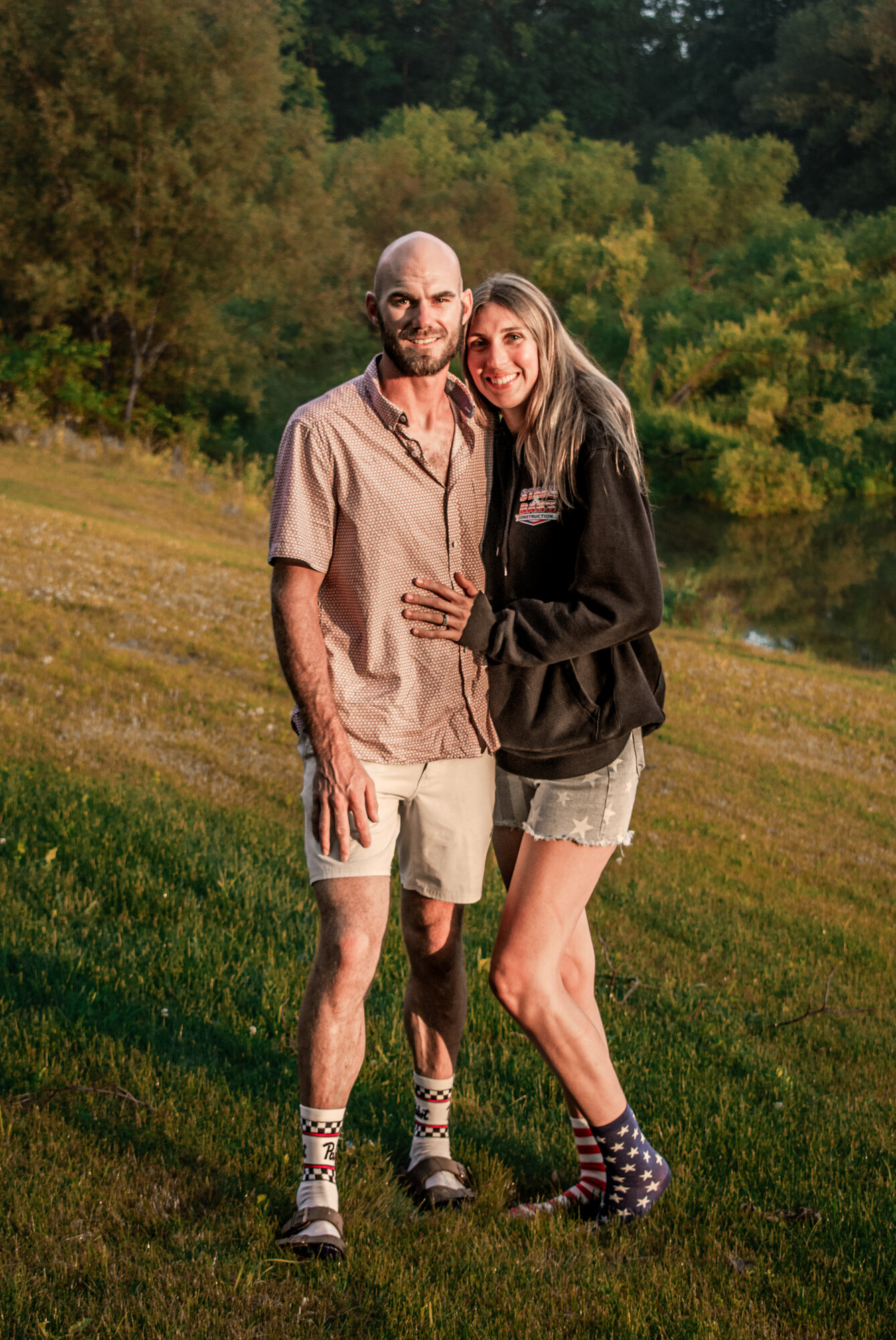Couple portrait at golden hour in a green riverside meadow, natural-light photography