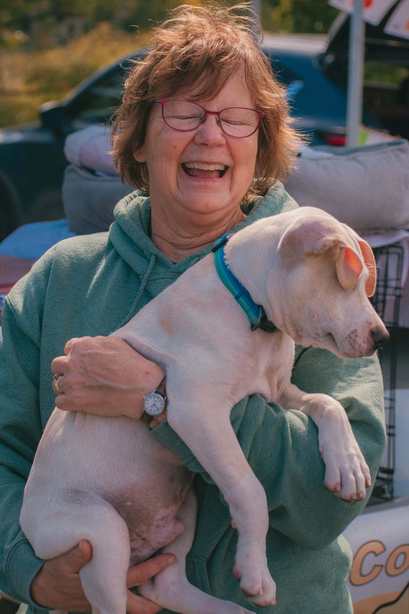 An adult attendee laughing while holding a puppy at Grove City Agway 2026 Petfest