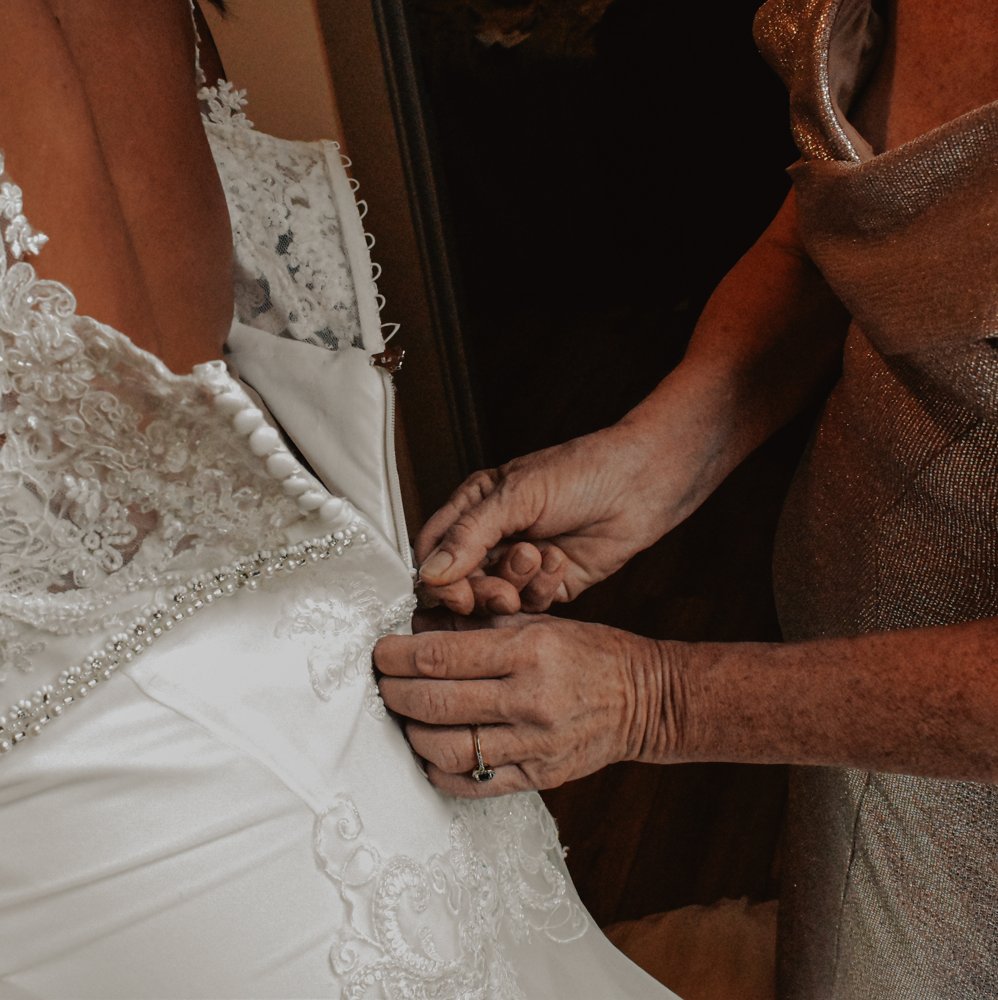 Close-up of hands fastening the bride's lace wedding dress