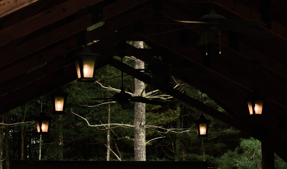 Warm hanging lanterns beneath the timber roof of a woodland pavilion
