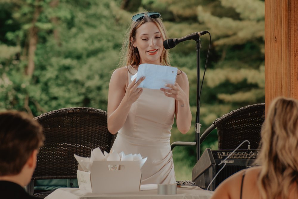 Wedding guest reading a speech into a microphone at the outdoor reception