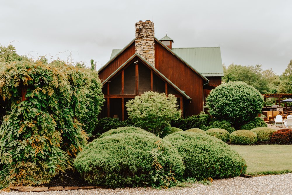 Rustic wedding lodge framed by lush shrubs and climbing greenery