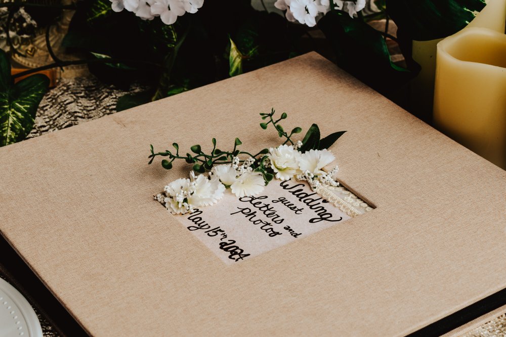 Wedding guestbook decorated with small white flowers beside a candle
