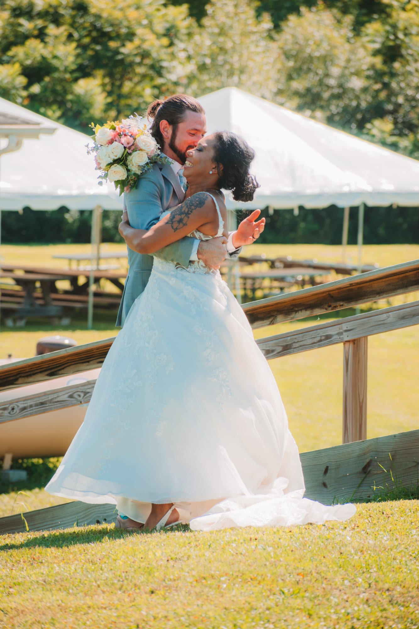 Newlywed couple embracing on the reception deck in bright summer light