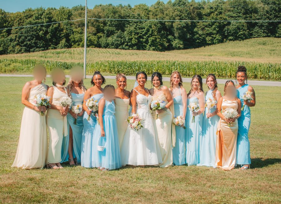 Full wedding party lined up across a sunlit field, with minors' faces blurred for privacy