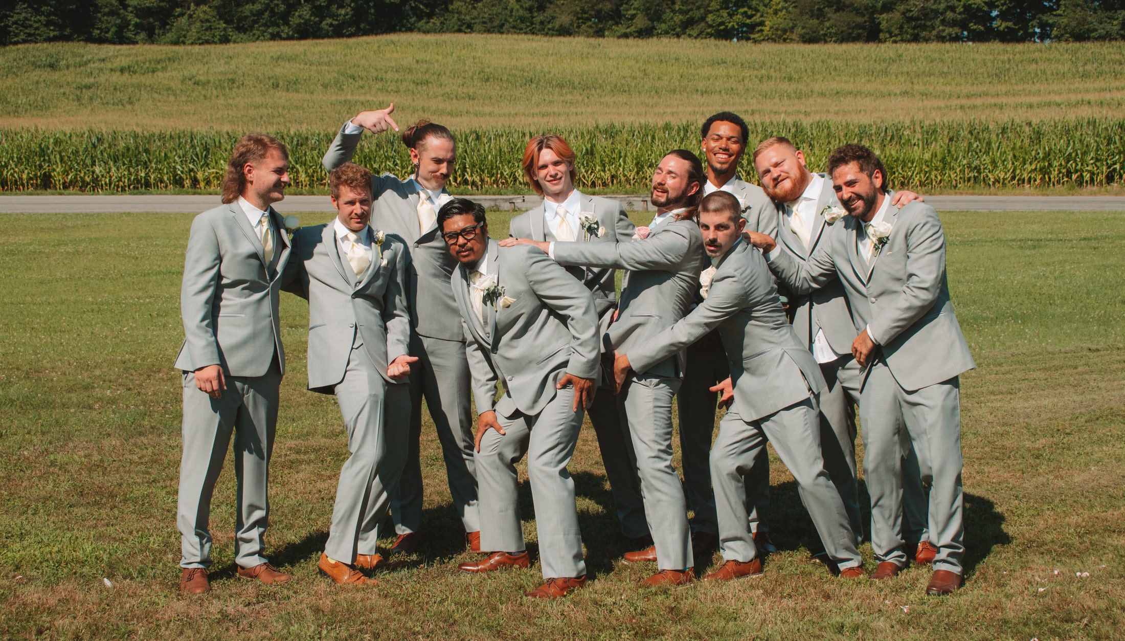 Adult groomsmen laughing together in a cornfield-side portrait