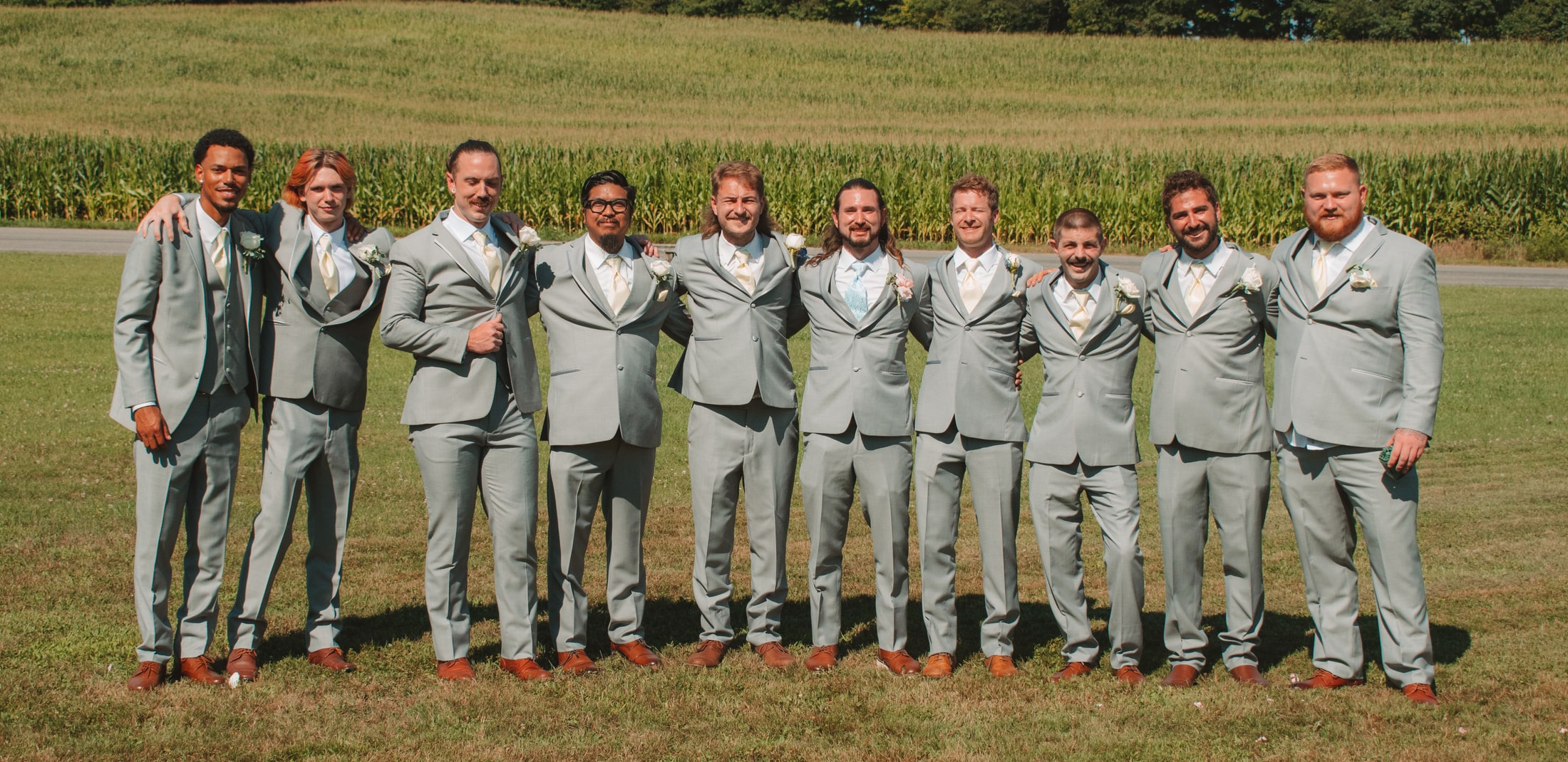 Full group of groomsmen standing together in coordinated light gray suits