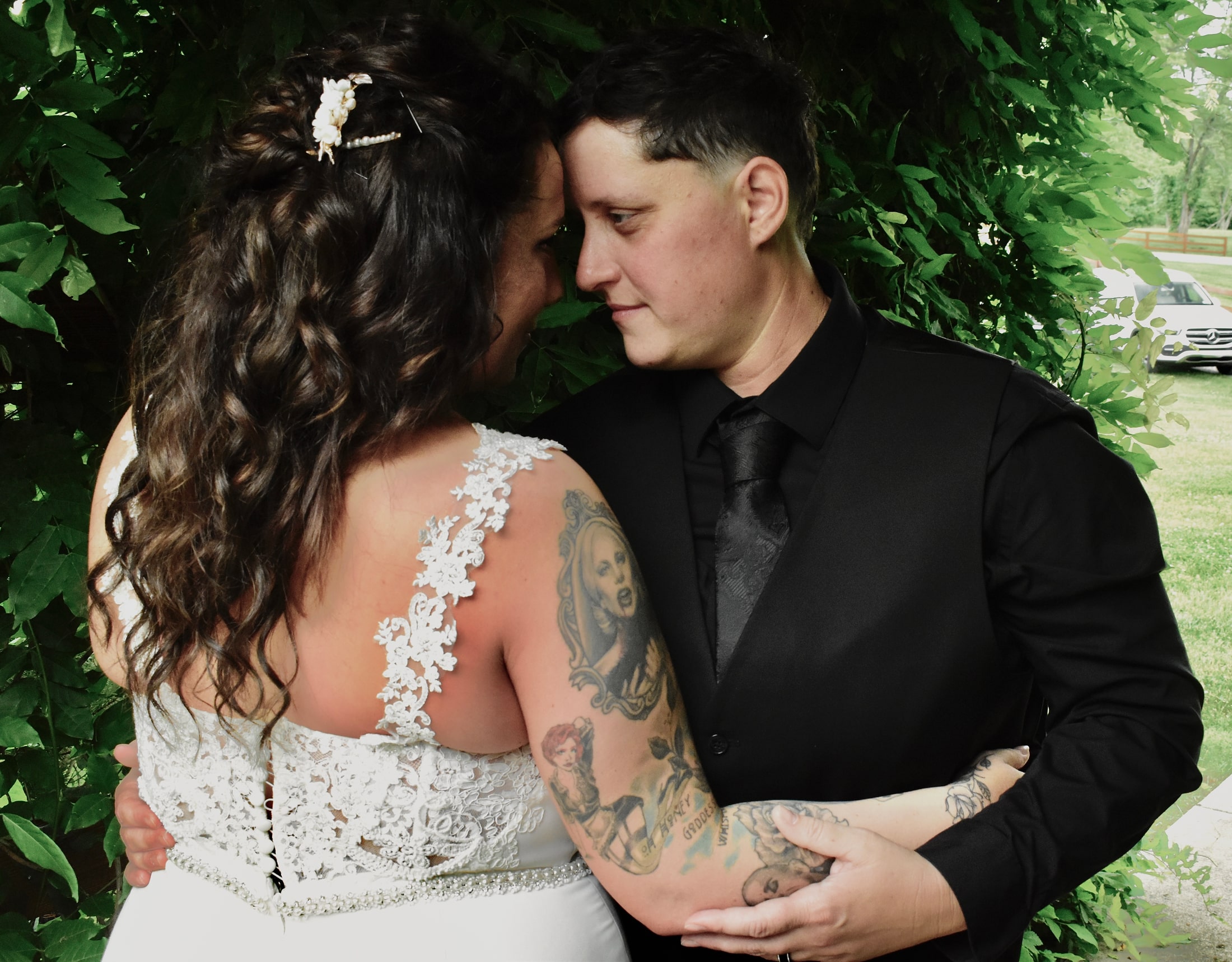 Intimate close portrait of a newlywed couple touching foreheads beneath green vines