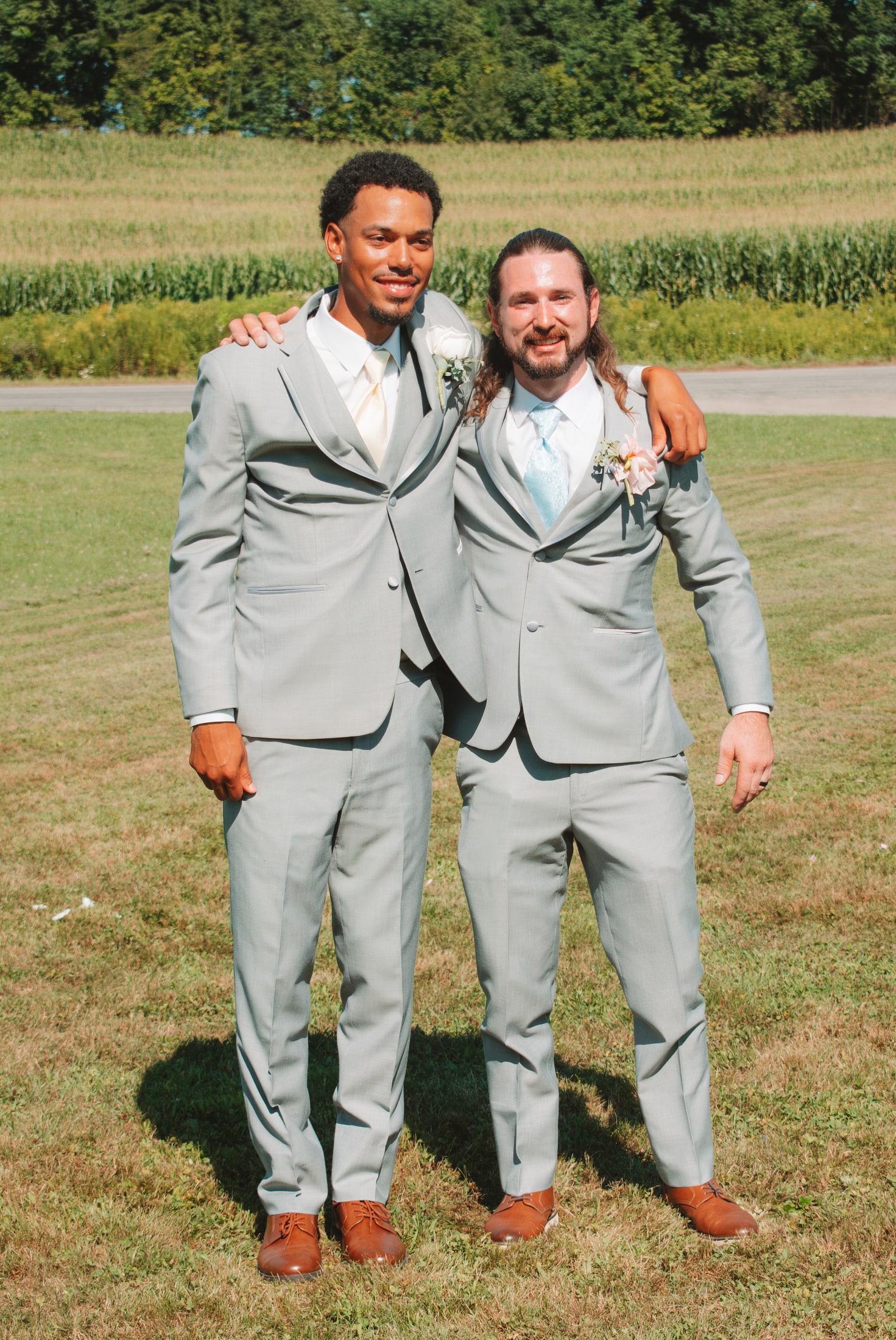 Closer portrait of two groomsmen smiling together on the lawn
