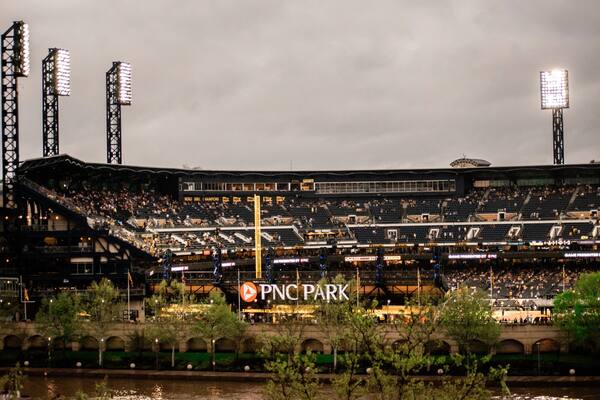 PNC Park baseball stadium at dusk with stadium lights and cloudy sky
