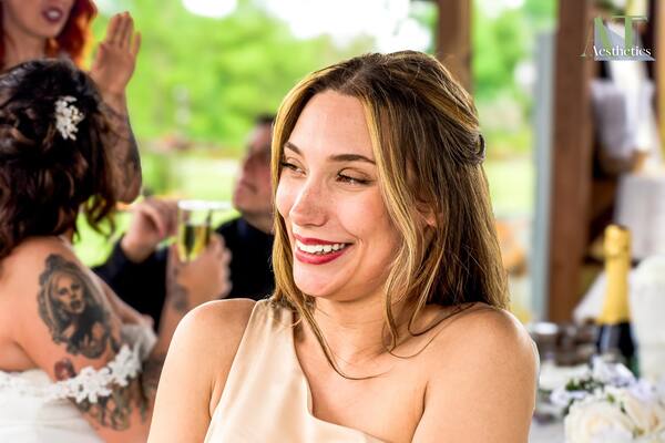 Smiling guest in a champagne dress enjoying an outdoor wedding reception