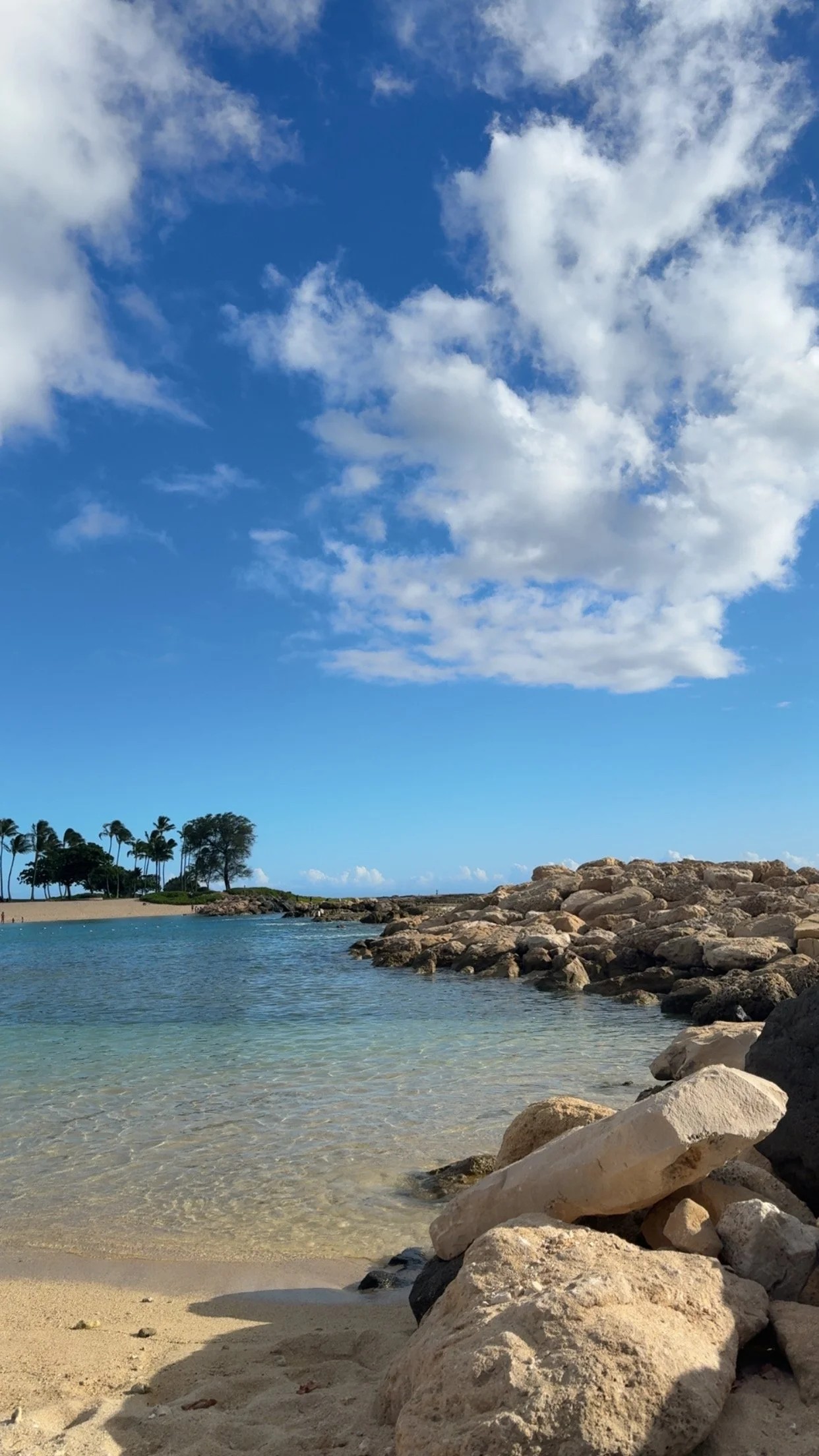 Tropical Hawaiian beach cove with rocks, clear water, and blue sky