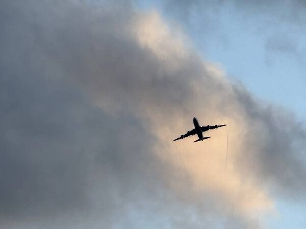 Airplane silhouette flying through dramatic cloudy sky at dusk
