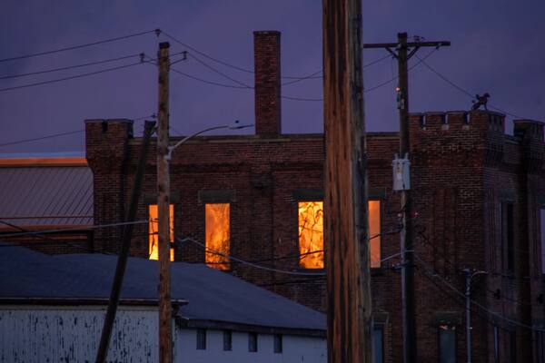 Old brick building at dusk with glowing orange windows and power lines