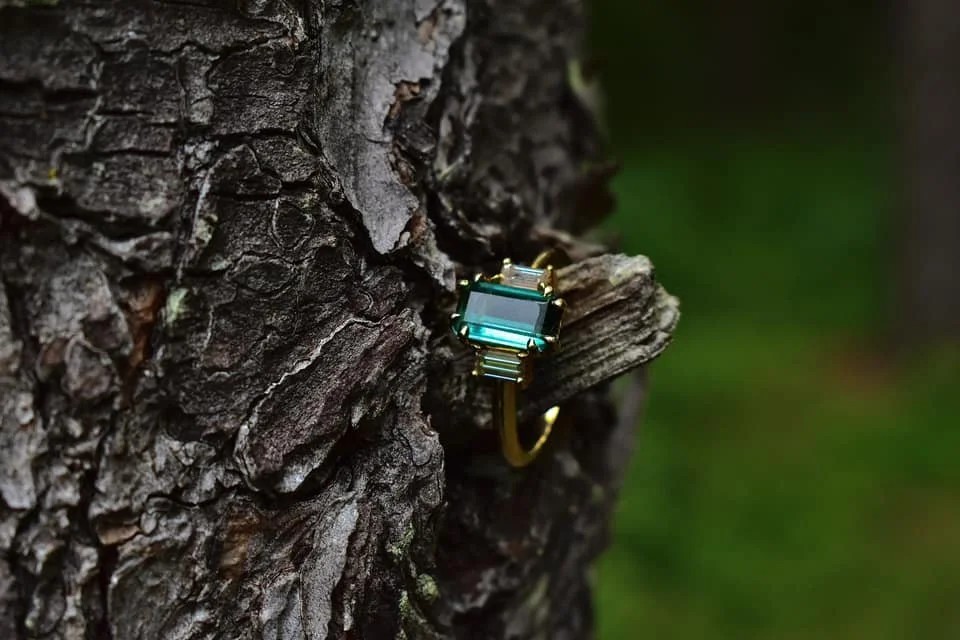 Emerald gemstone ring resting on tree bark
